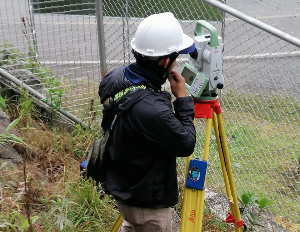Profesional utilizando una estación total para un levantamiento topográfico.